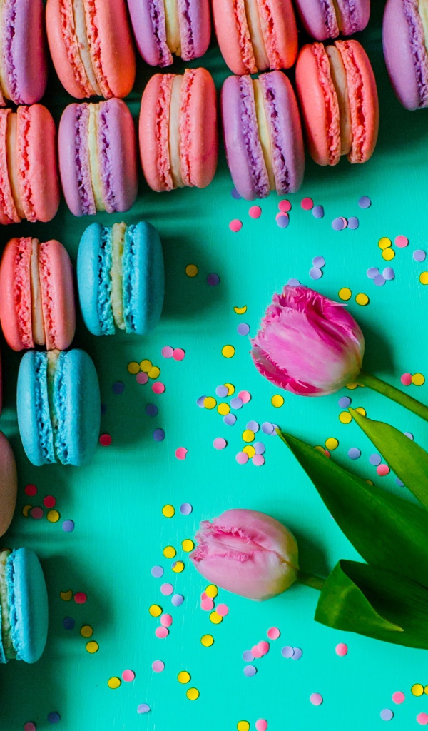 Разноцветные десерты макарун на столе с тюльпанами