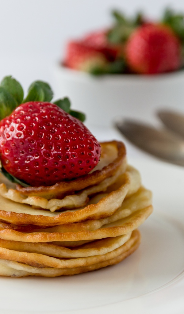 Оладьи с ягодами свежей клубники на белой тарелке 