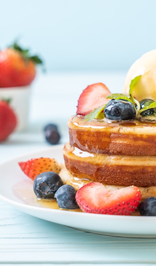 Оладья и медом, мороженым и ягодами черники и клубники на столе