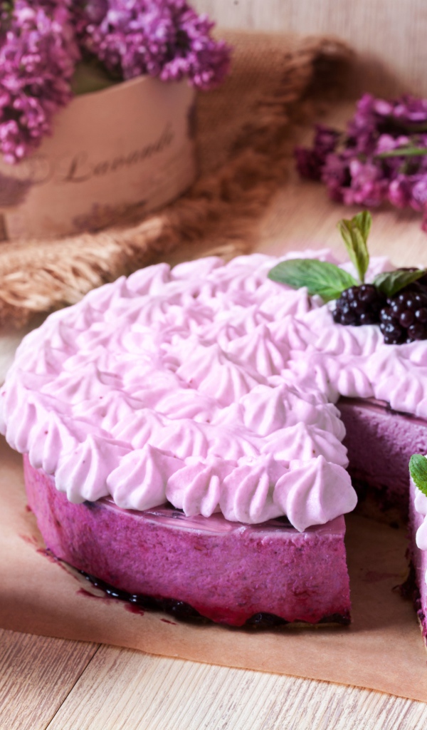 Пирог с кремом и вкусными кексами с черникой на столе с цветами сирени