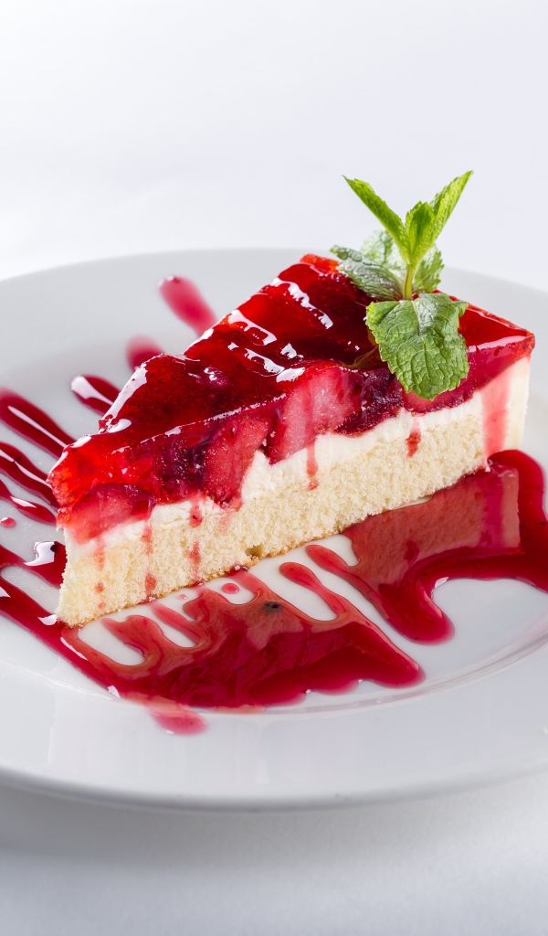 Кусок пирога с клубникой и джемом на белой тарелке