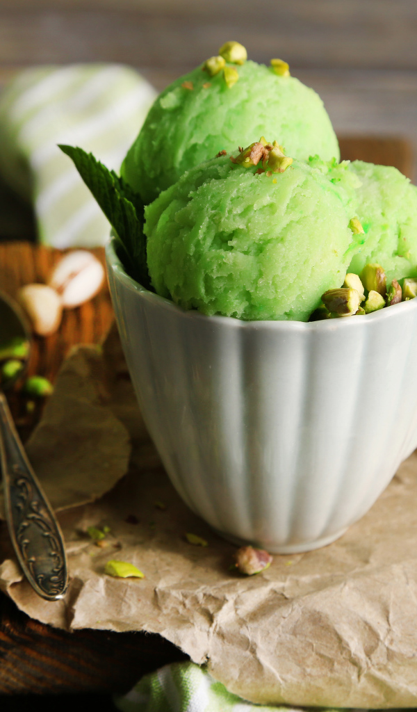 Фисташковое мороженое в белой чашке на столе