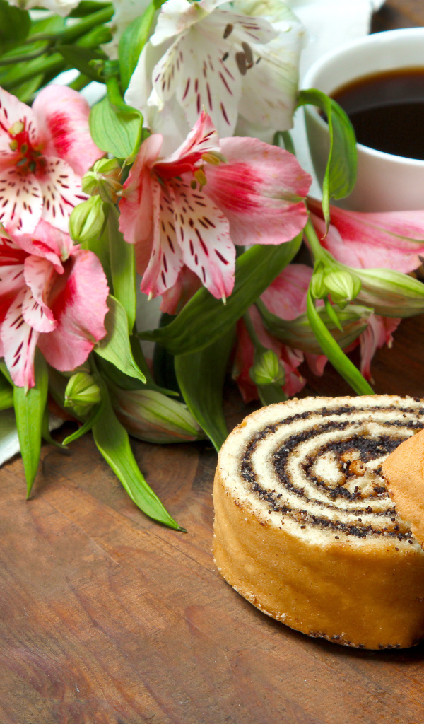 Рулет с маком на столе с цветами альстрёмерия и чашкой кофе