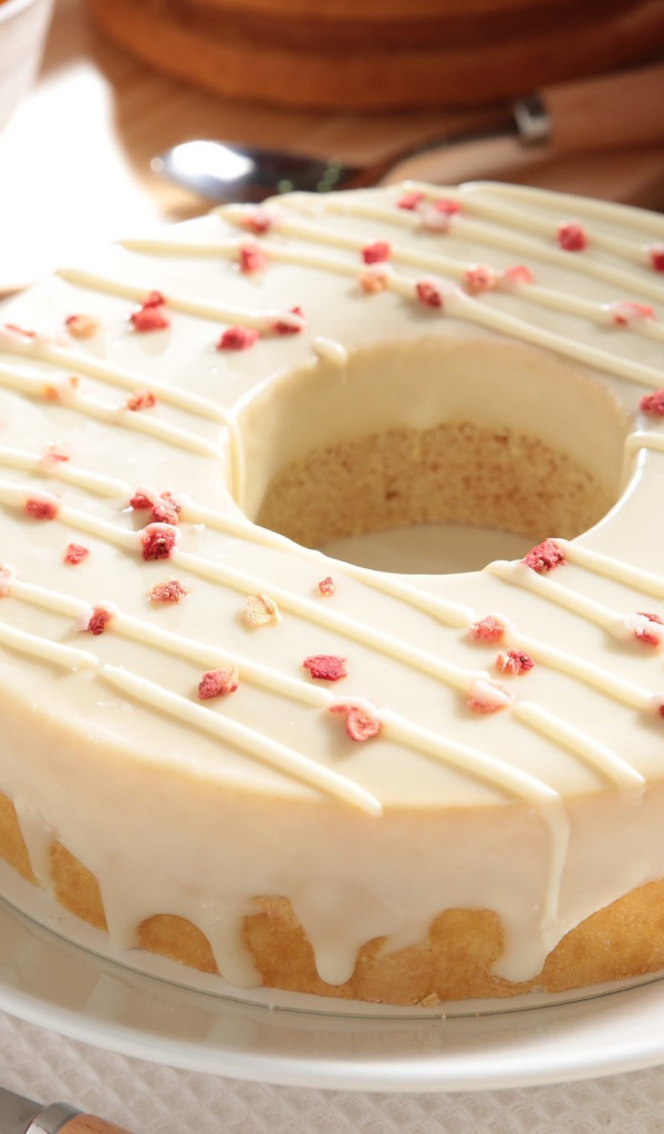 Круглый кекс с глазурью на белом блюде 