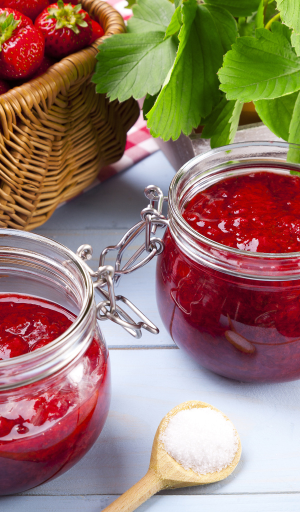 Клубничное варенье в стеклянных баночках на столе  ягодами