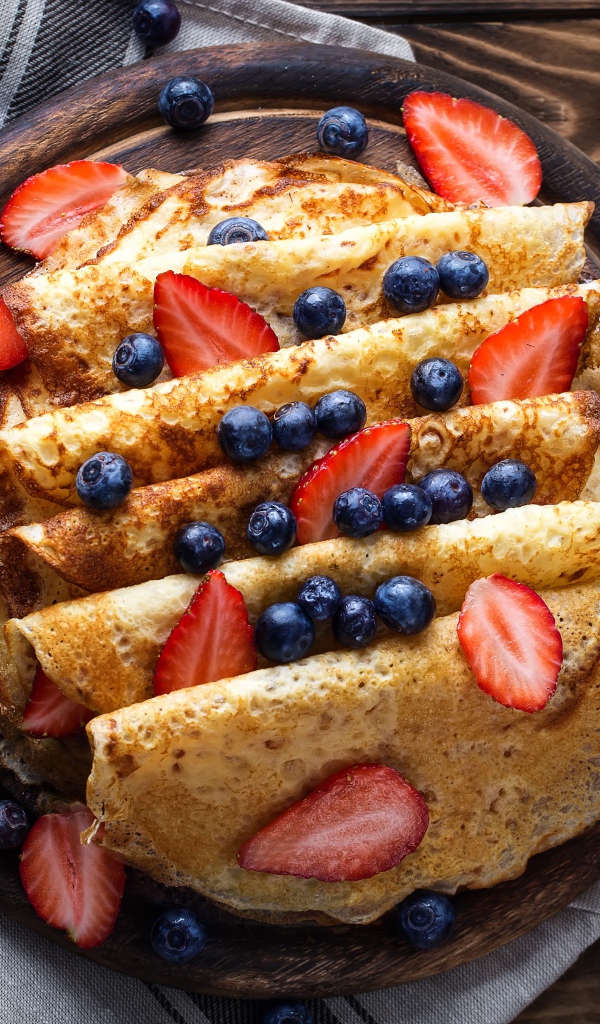 Сладкие блины с ягодами черники и клубники на столе