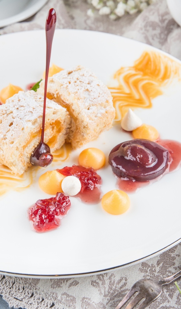 Сладкий рулет с сухофруктами и джемом на тарелке 