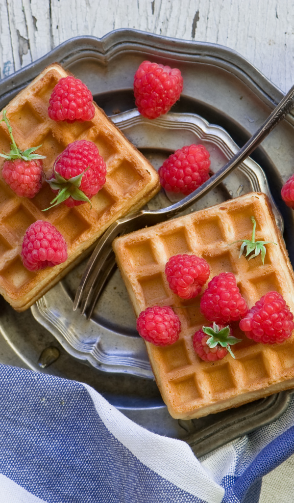 Сладкие вафли с ягодами малины на столе 