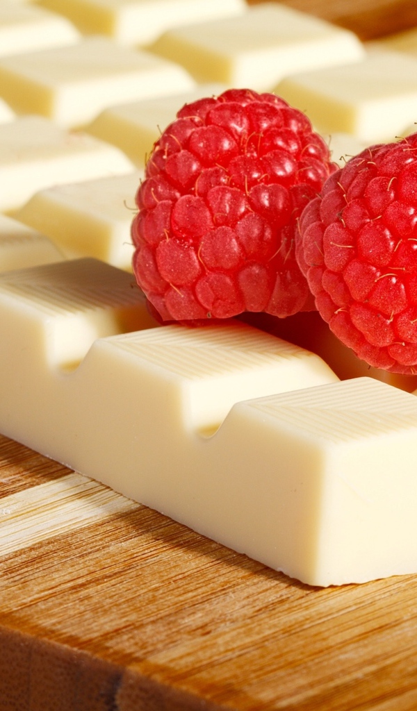 Сладкий белый шоколад с ягодами малины на столе