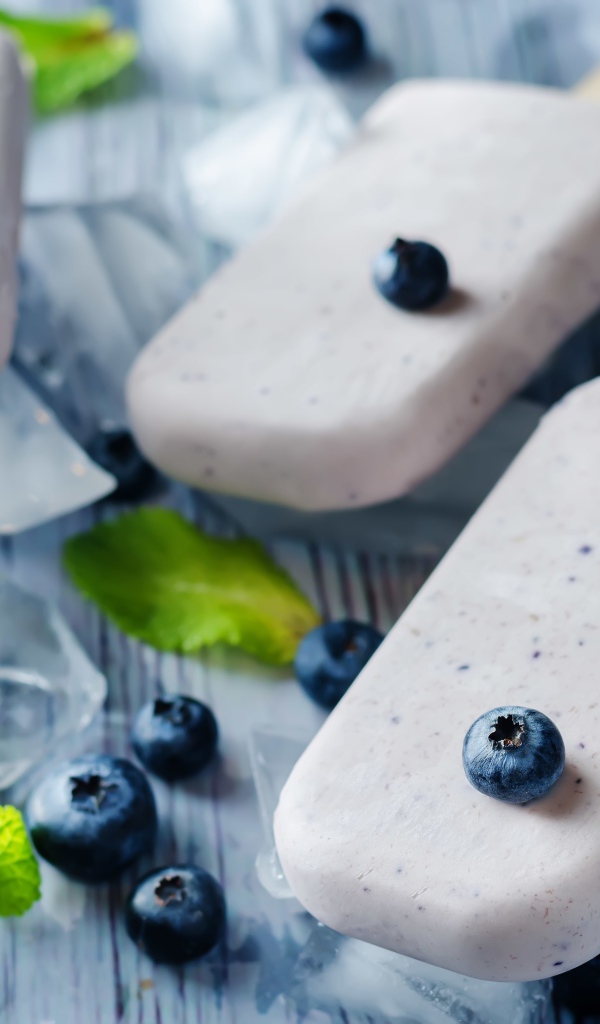 Вкусное мороженое с ягодами черники на столе с кусочками льда