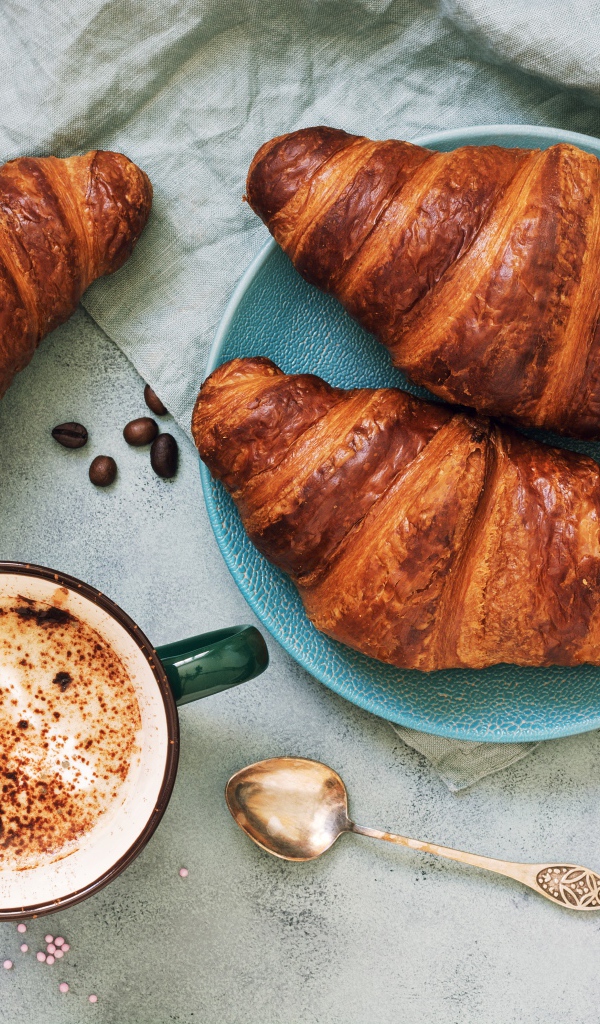 Три круассана на столе с чашкой кофе