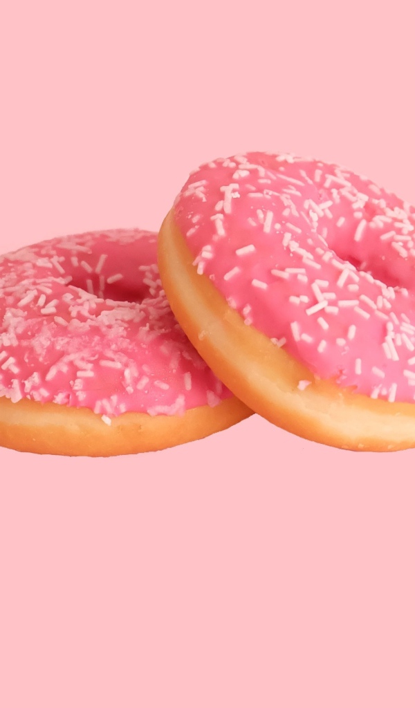 Два пончика с глазурью на розовом фоне