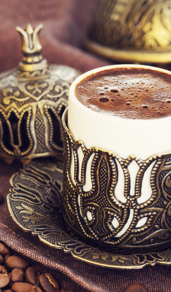 Красивая дизайнерская чашка кофе на столе с зернами