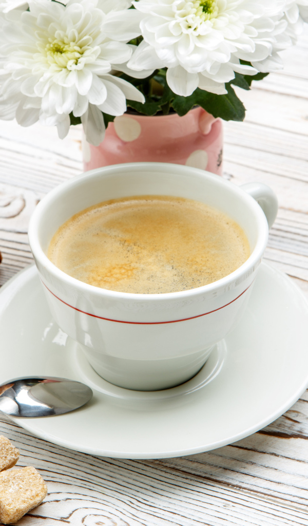 Чашка кофе и круассаны на столе с белыми хризантемами 