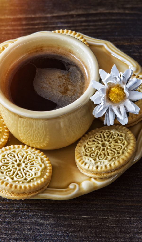 A cup of coffee on a saucer with biscuits