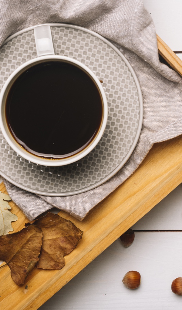 Чашка кофе на столе с лесными орехами и желтыми листьями