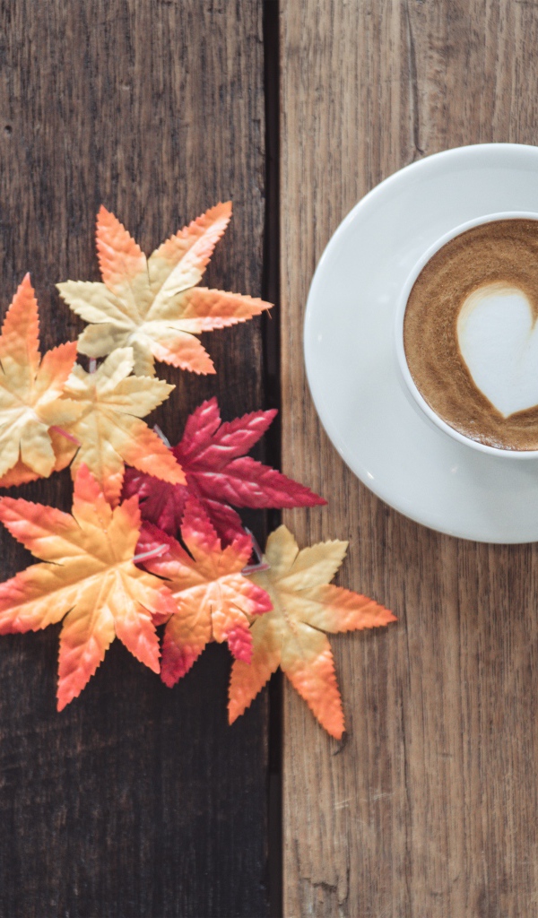 Чашка кофе на деревянном столе с желтыми листьями