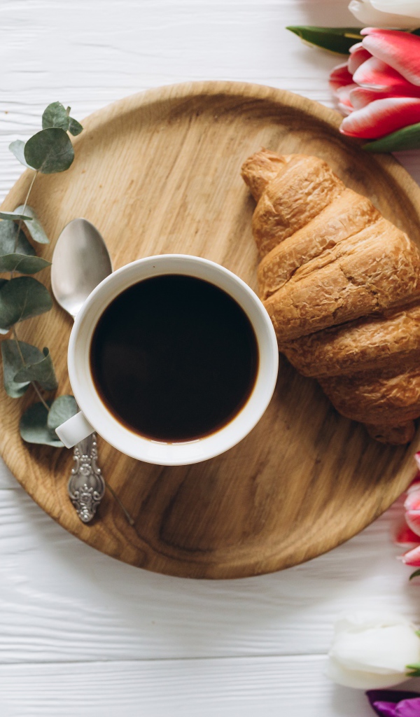 Чашка кофе с круассаном на столе с букетом тюльпанов 