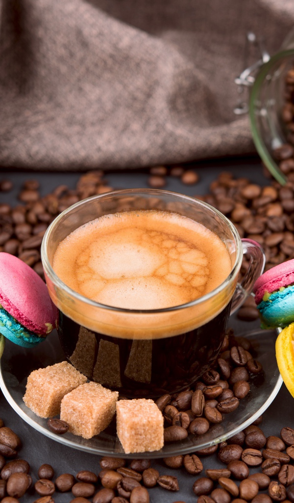 Чашка кофе с кофейными зернами, кубиками сахара и десертом макарон