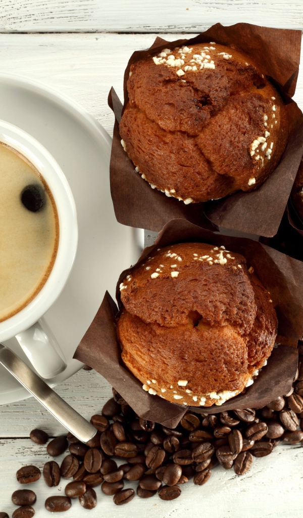 Чашка кофе с кексами и кофейными зернами на столе