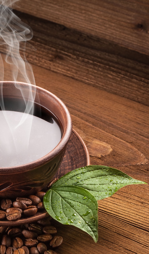 Чашка горячего кофе с зернами на деревянном столе