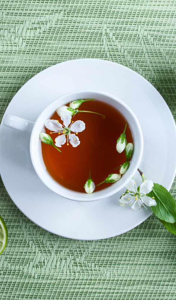 A cup of tea with green limes on the table