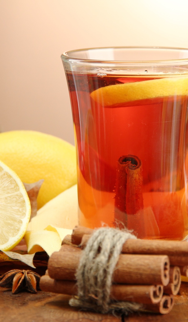 Чашка чая с лимоном и корицей на столе с лимонами