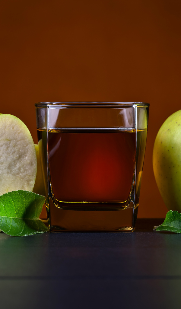 Стакан яблочного сока на столе с зелеными яблоками