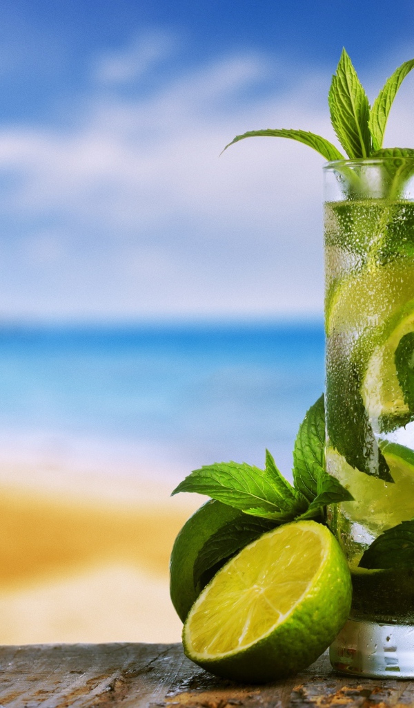 Стакан холодного мохито на столе с мятой и лаймом