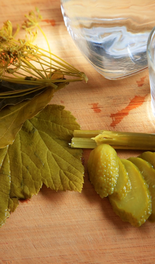 Рюмка водки на столе с соленым огурцом