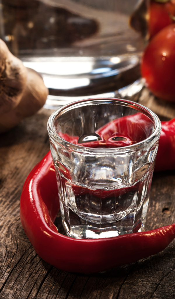 Рюмка водки на столе с красным перцем и чесноком