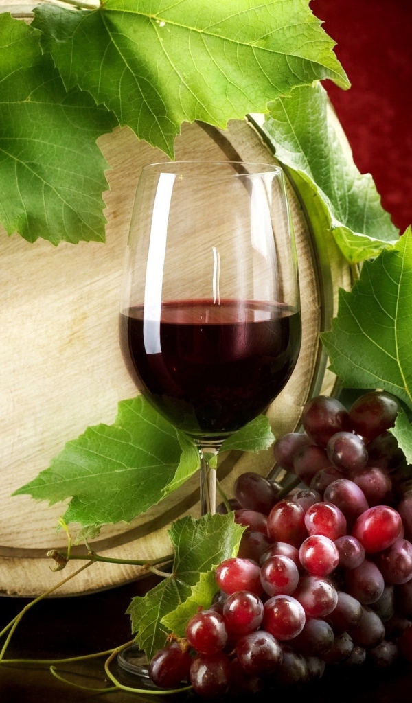 Бокал вина на столе с гроздью винограда и бочкой