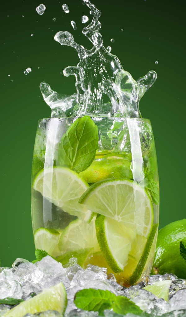 Стакан с лимонадом стоит на кусочках льда с лаймом