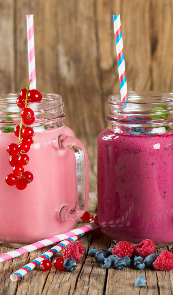 Ягодное смузи в баночках на столе со свежими ягодами малины, смородины и черники