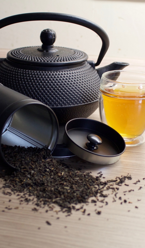 Черный чай на столе с чайником и чашкой