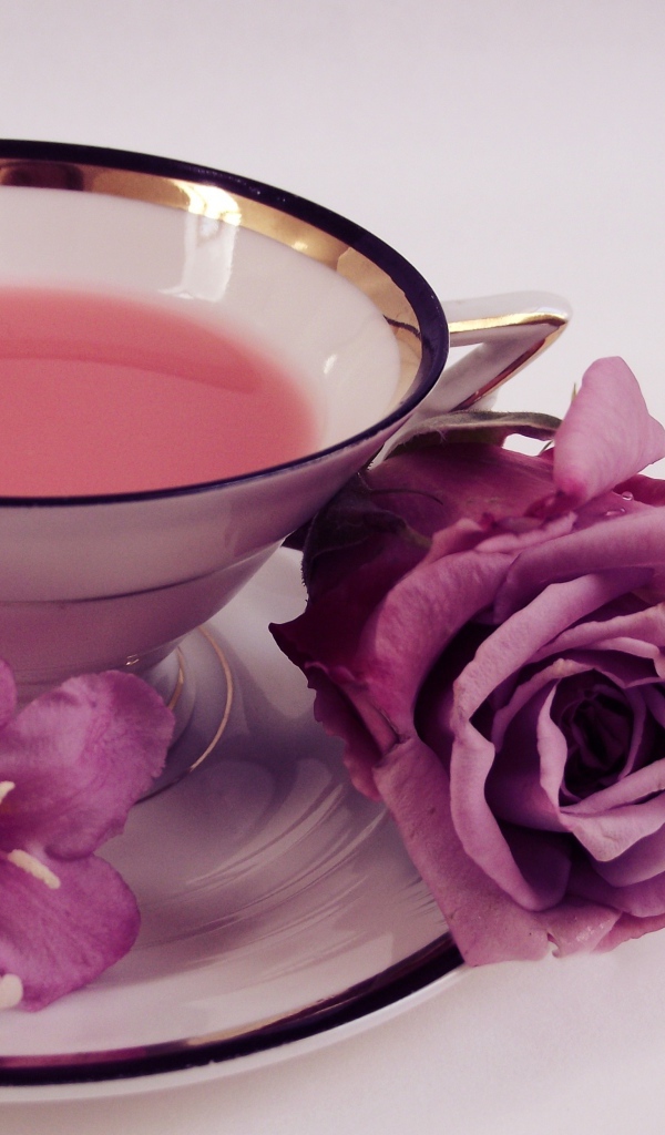 Чашка чаю на тарелке с розой и колокольчиками на сером фоне