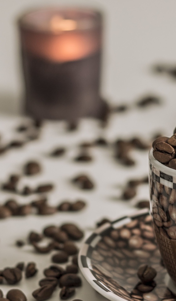 Чашка с кофейными зернами на столе со свечами