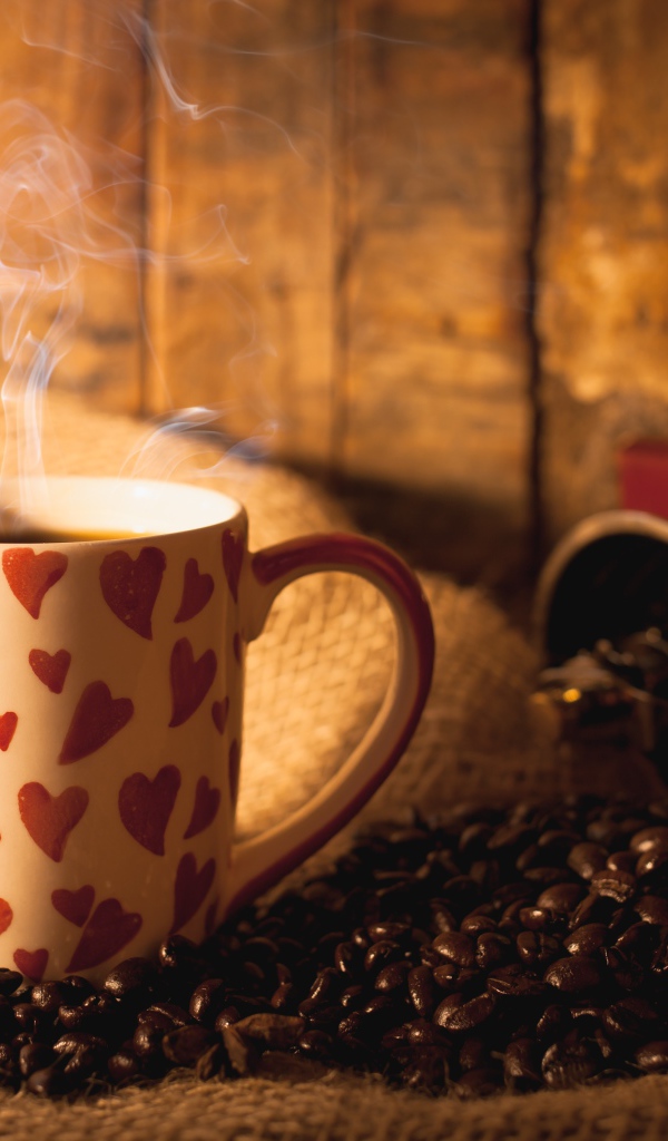 Чашка с горячим кофе на столе с кофейными зернами и корицей