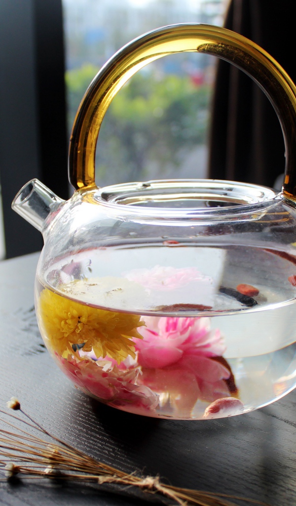 Цветочный чай в стеклянном чайнике на столе 