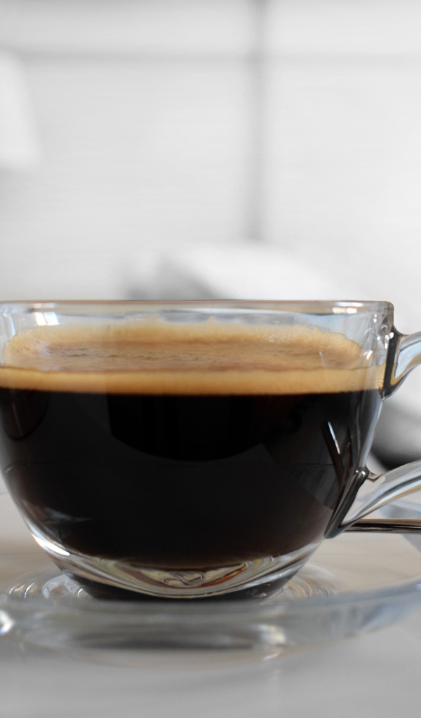 Стеклянная чашка кофе на блюдце с ложкой