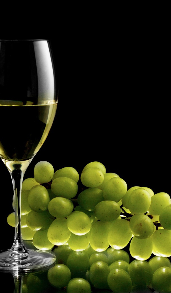 Бокал белого вина с белым виноградом на черном фоне
