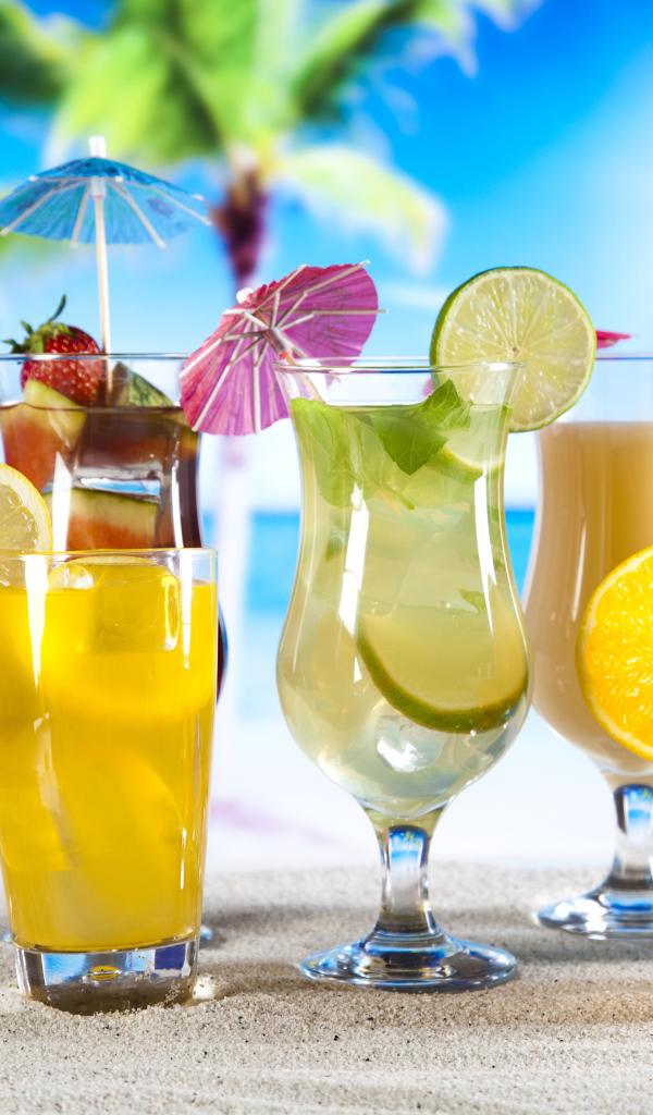 Бокалы с тропическими коктейлями на песке на пляже