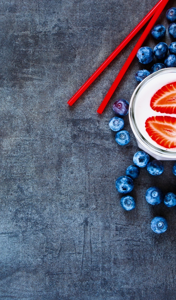 Молочный коктейль с клубникой и черникой на столе 