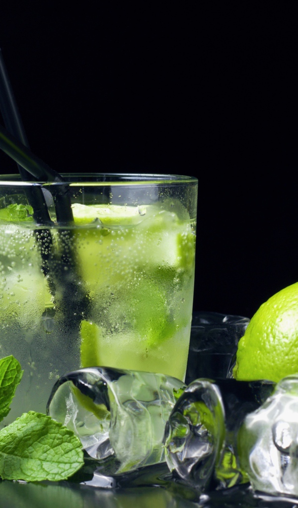 Коктейль мохито на черном фоне с лаймом и кубиками льда