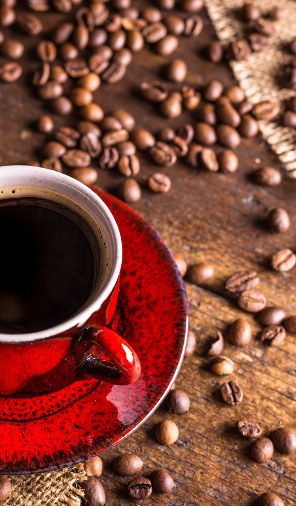 Красная чашка кофе на столе с зернами кофе