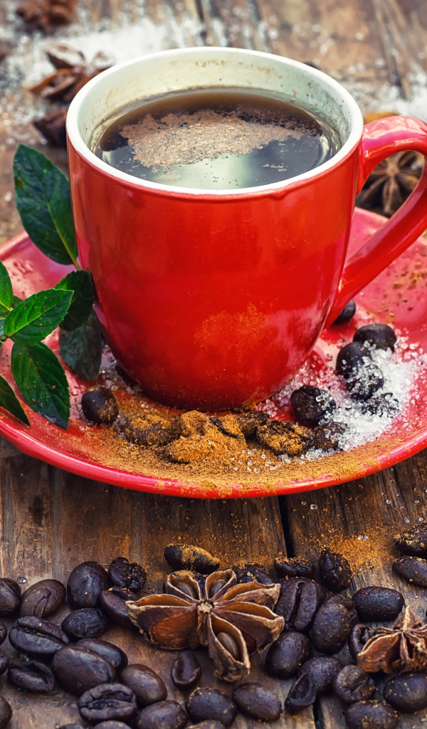 Красная чашка кофе на столе с зернами  и бадьяном и корицей