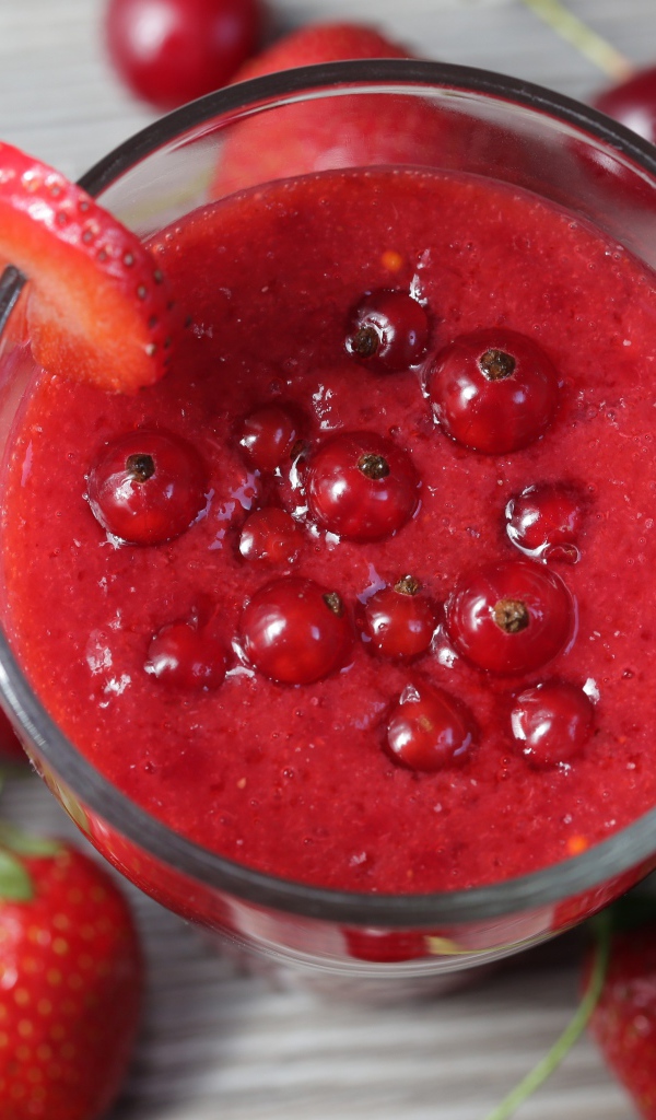 Смузи в стакане с ягодами клубники, красной смородины и вишни