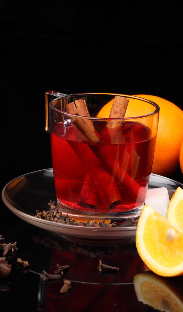 Чай с корицей и кусочками апельсина на черном фоне