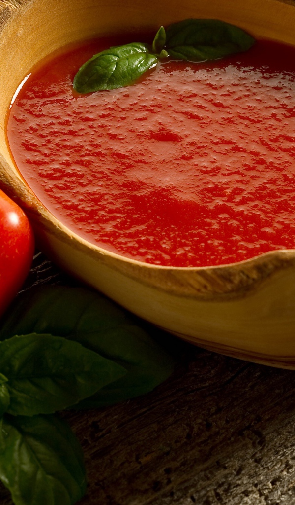 Томатный сок в деревянной посуде на столе с помидорами и базиликом