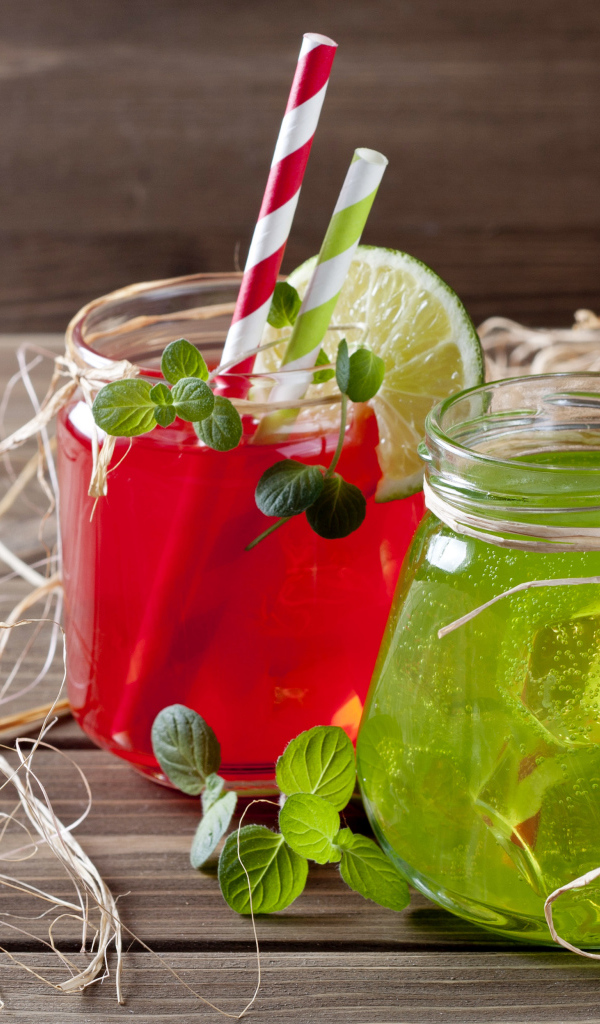 Две банки с коктейлями на деревянном столе с соломой